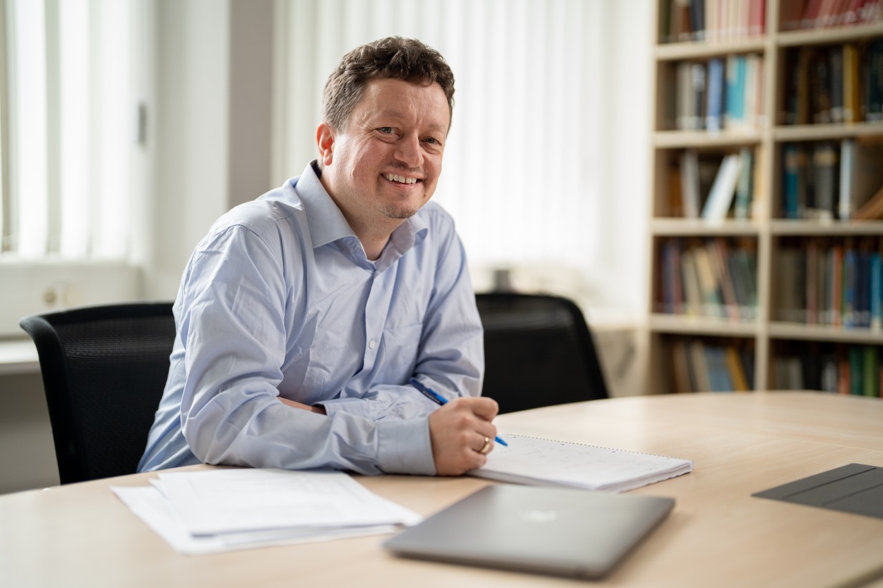 Peter Rabl sitting at his desk and writiing on a notepad.