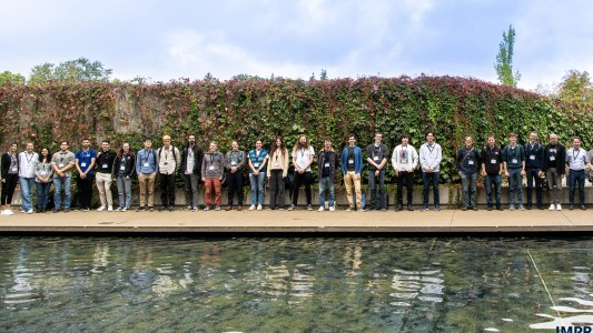 Group picture of researchers in front of an evergreen fence.